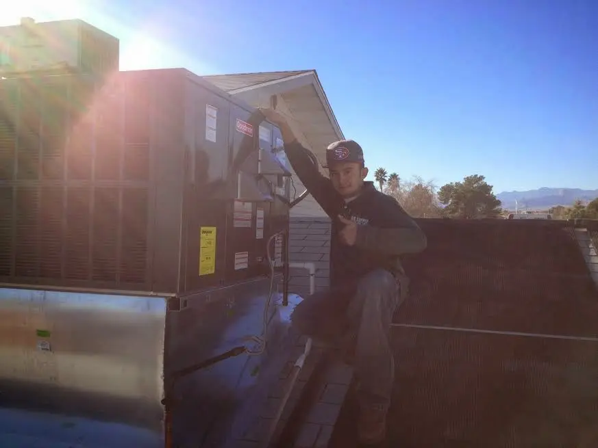 HVAC technician performing Boiler Repair on a rooftop unit in Hamilton